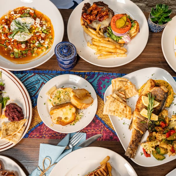 An overhead view of a table laden with various Mediterranean dishes, including seafood, burgers, and appetizers.